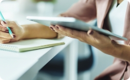 Woman taking notes while viewing tablet