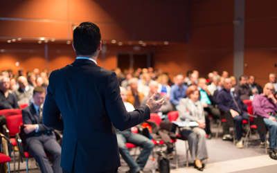 back of a male speaking to a crowd 