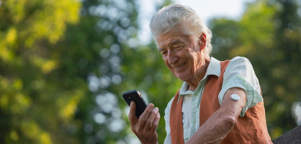 senior diabetic man checking his glucose data on smartphone outd